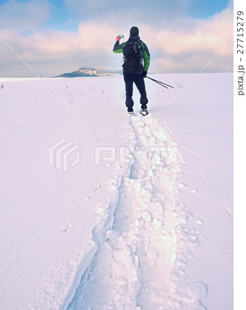 Man with snowshoes take photos by smartphone.  27715279