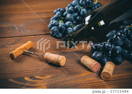 Bottle of wine, grape and corks on wooden table Bottle of wine, grape and corks on wooden table 27715494
