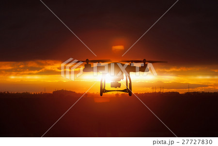 Silhouette of flying drone in glowing sunset sky 27727830