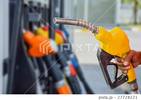 Holding a fuel nozzle against with gas station. Holding a fuel nozzle against with gas station. 27728221