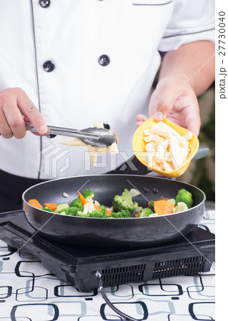 Chef putting baby corn to pan Chef putting baby corn to pan 27730040