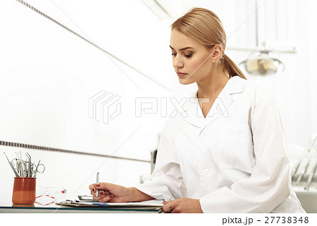 Odontologist filling up a form in office 27738348