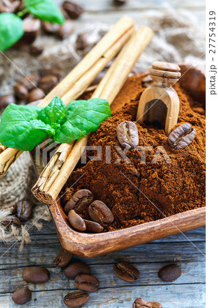 Ground coffee and cinnamon sticks in wooden bowl. 27754319