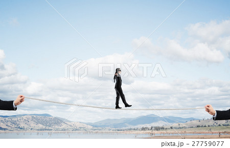 Business concept of risk support and assistance with man balancing on rope 27759077