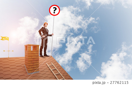 Businessman on brick house roof showing banner with question mark. Mixed media Businessman on brick house roof showing banner with question mark. Mixed media 27762115