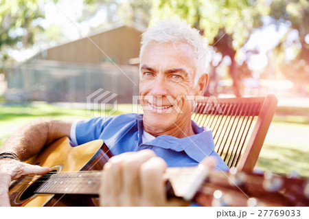Senior man plying guitar outdoors Senior man plying guitar outdoors 27769033