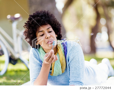 Beautiful woman blowing bubbles in park Beautiful woman blowing bubbles in park 27772044