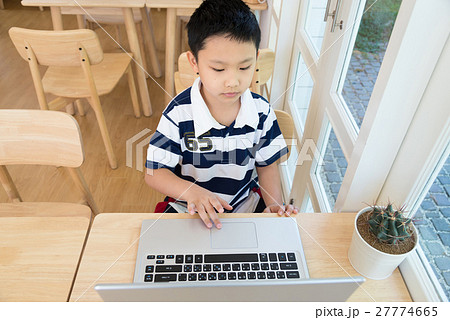 Asian boy sitting at his desk with laptop computer 27774665