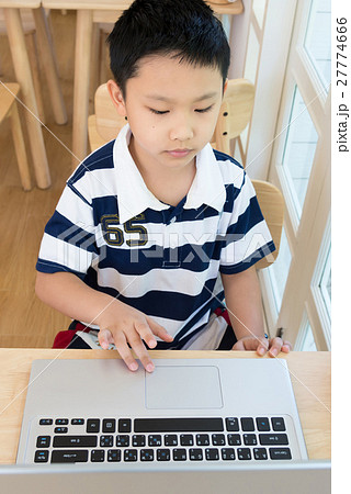 Asian boy sitting at his desk with laptop computer 27774666