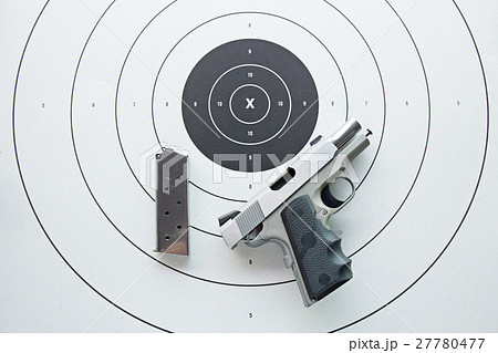 silver .45 pistol with magazine on bullseye target 27780477