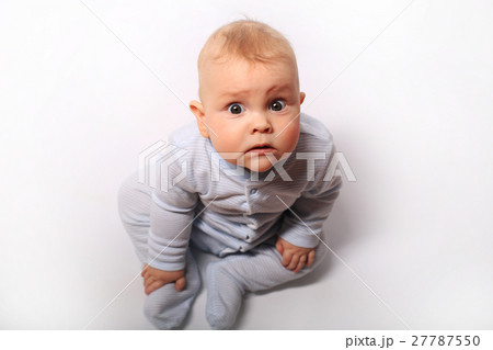 baby sits in a blue dress on the bed 27787550
