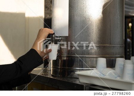 Woman filling plastic cup at water cooler 27798260
