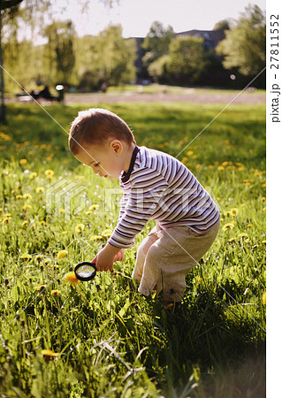 boy child magnifying glass exploring meadow 27811552