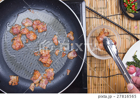 Chef holding crispy bacon to cup by tongs Chef holding crispy bacon to cup by tongs 27816565
