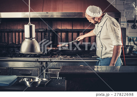 Busy chef at work in the restaurant kitchen Busy chef at work in the restaurant kitchen 27822698