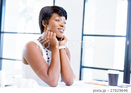 Young woman sitting at a desk in an office and working on blueprint 27829646