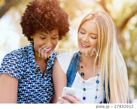 Two women friends in park with mobile phone 27832012