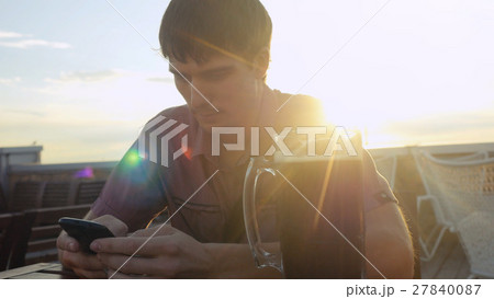 Young brunette man with smartphone eating and 27840087