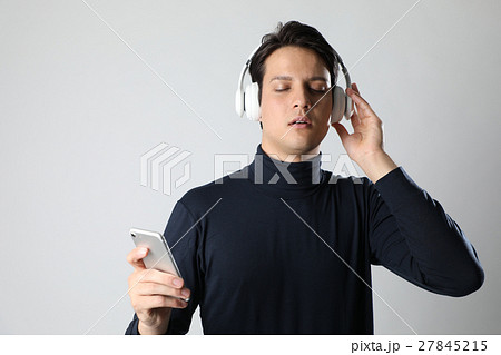 ワイヤレスヘッドホンとスマホで音楽を聴く男性の写真素材