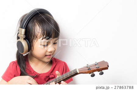 Asian girl is practicing guitar wearing headphone Asian girl is practicing guitar wearing headphone 27863788