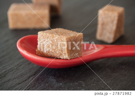 closeup of cubes of sugar in a red spoon  27871982