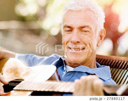 Senior man plying guitar outdoors 27880117
