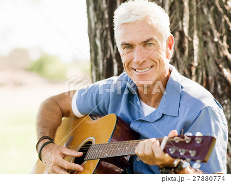 Senior man plying guitar outdoors Senior man plying guitar outdoors 27880774