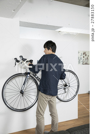 自転車を部屋から運ぶ男性 ポートレートの写真素材