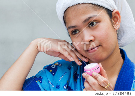 Woman applying moisturizer cream on her pretty face 27884493