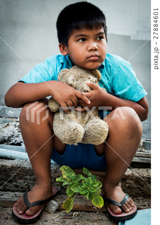 Boy poor with old teddy bear sitting on old wood pile Boy poor with old teddy bear sitting on old wood pile 27884601