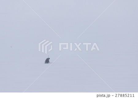 lonely fisherman sitting on the frozen river 27885211