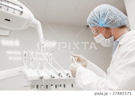 Dentist leaned over patient in 's chair at clinic Dentist leaned over patient in 's chair at clinic 27885575