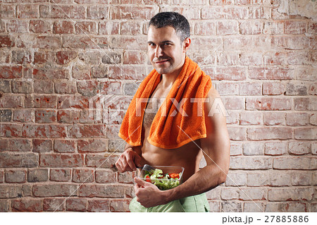 Fit man holding a bowl of fresh salad on old red 27885886