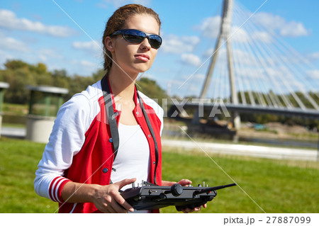 Woman with remote control and flying drone Woman with remote control and flying drone 27887099