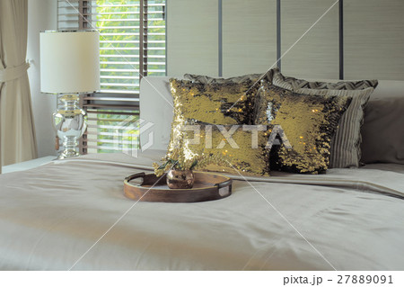Wooden tray with golden glitter pillows on bed 27889091