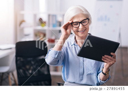 Delighted aged businesswoman enjoying new gadget Delighted aged businesswoman enjoying new gadget 27891455