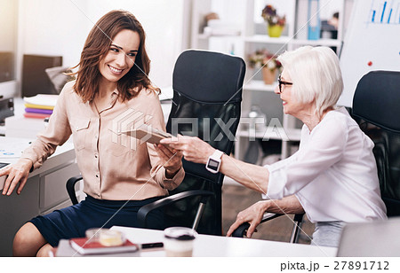 Smiling pleasant businesswomen sharing papers in 27891712