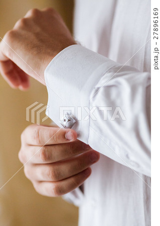the man corrects cuff links on a shirt. the groom 27896169