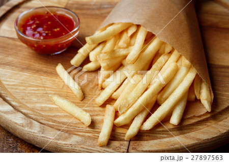 Fried potato chips wrapped takeaway on wood Fried potato chips wrapped takeaway on wood 27897563