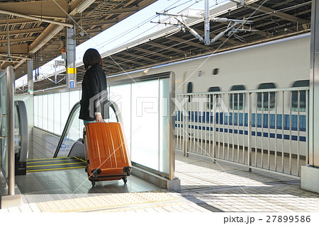 新幹線の駅でスーツケースを持つ女性旅行者 27899586