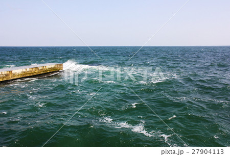 Old concrete, stone pier into the sea. Old concrete, stone pier into the sea. 27904113