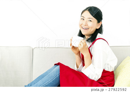 ソファーに横座りしカメラ目線でコーヒーを飲む女性 27922592