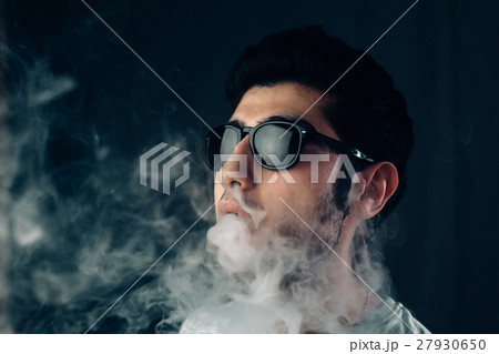 Young cool guy in sunglasses exhales a cloud of 27930650
