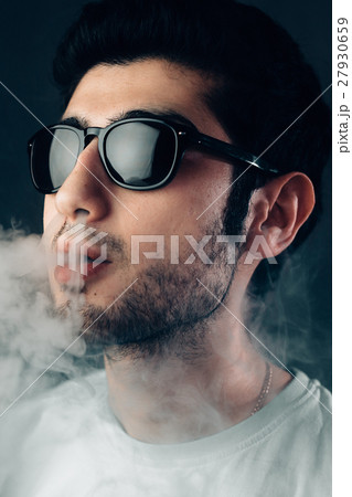 Young cool guy in sunglasses exhales a cloud of 27930659