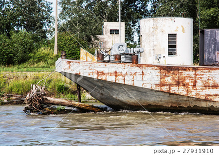 Old rusty anchored boat by riverside 27931910