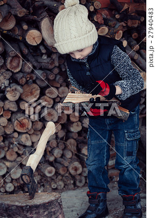 Little boy chopping firewood in the front yard at the day time. Little boy chopping firewood in the front yard at the day time. 27940483