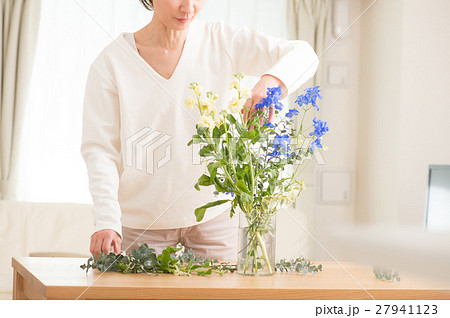 リビングで美しい花を活ける中年女性の写真素材