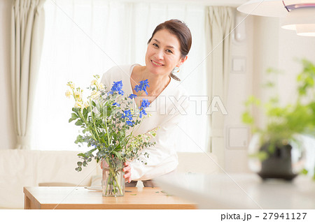リビングで美しい花を活ける中年女性の写真素材