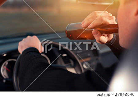 Young man drinking beer while driving a car 27943646
