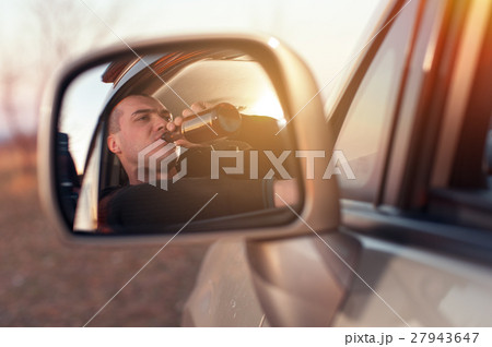 Young drunk man driving a car and drinking beer Young drunk man driving a car and drinking beer 27943647